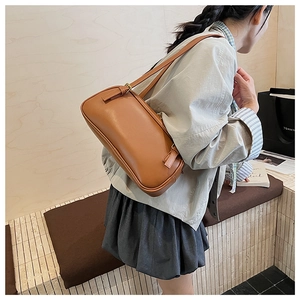 Detail view of the brown leather shoulder bag featuring fine texture and adjustable strap