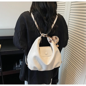 Detail view of white crescent bag with pleated PU leather and cute brown teddy bear charm