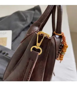 Close-up of dark brown leather handbag featuring gold metal hardware and wood bead charms