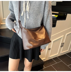 Detail view of the deep brown leather tote bag with a metal logo on a model