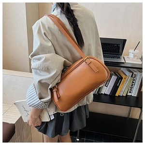 Detail view of a vintage caramel leather baguette bag worn as a shoulder bag on a model