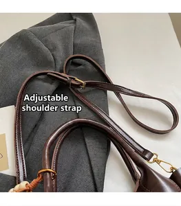 Detail of adjustable dark brown leather shoulder strap with polished gold metal buckles
