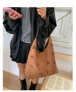 Detail of laser-cut floral patterns on brown faux suede leather tote shoulder bag
