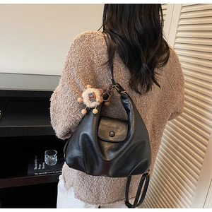 Back view of a black soft leather shoulder bag with a cute plush lion charm pendant