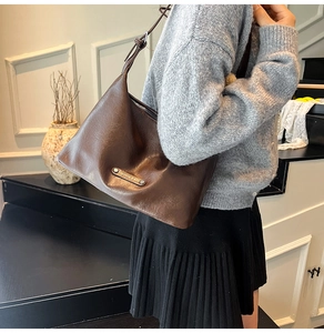 Detail of deep brown soft leather hobo bag with silver zipper and metal brand tag