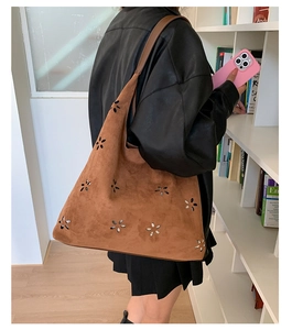 Detail of laser-cut floral pattern on caramel faux suede hobo bag with bohemian design