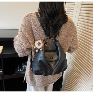 Detail of black wrinkled PU leather hobo bag with a cute lion plush pendant on a model