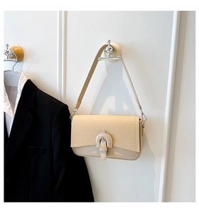 Detail view of cream quilted shoulder bag with woven texture and horseshoe buckle accent