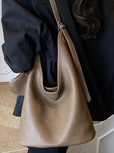 Minimalist brown pebbled leather bucket bag with wide adjustable strap for women