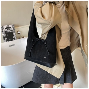Détail du sac hobo en daim noir avec nœud délicat et emblème de cœur argenté