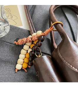 Close-up of bohemian wood bead charm with fringe on vintage brown leather handbag