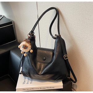 Detail of black matte leather shoulder bag with a cute brown alpaca plush charm