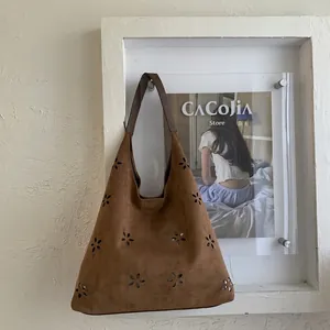 Detailed laser-cut floral patterns on a brown suede shoulder bag with retro design