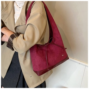 Détail du sac cabas en daim bordeaux avec nœud décoratif et petit charme en cœur