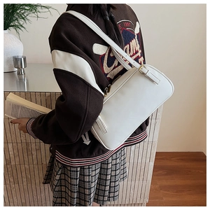 Detail showing an ivory white baguette shoulder bag worn by a model in a minimalist room