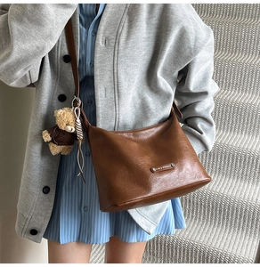 Brown faux leather hobo bag with silver logo plate and a cute teddy bear charm detail