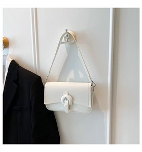 Close-up of a white textured leather crossbody bag with silver buckle on a hanger