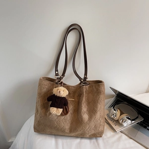 Detailed close-up of brown suede tote bag with quilted diamond pattern and bear charm