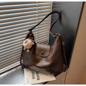 Detail view of dark brown oil wax leather hobo bag with cute sheep charm accessory