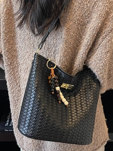 Chic black woven leather bucket bag with gold twist lock and beaded tassel charm