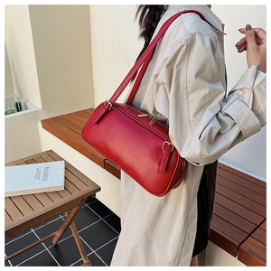 Detail view of a vintage red leather baguette bag on a trench coat shoulder