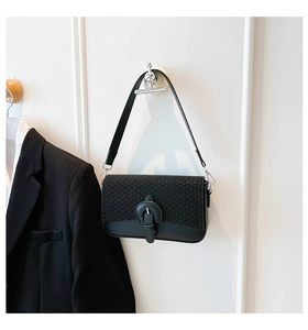 Detail of tweed and leather patchwork crossbody bag with black buckle on white wall
