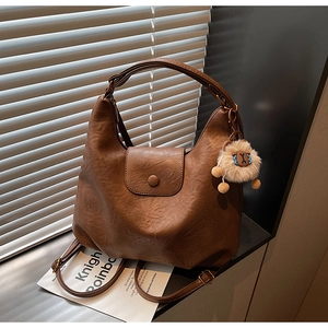 Detail of dark brown PU leather tote bag with a cute plush sheep pendant in natural light
