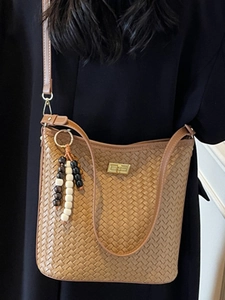Chic brown woven bucket bag with elegant metallic gold clasp and decorative bead charm