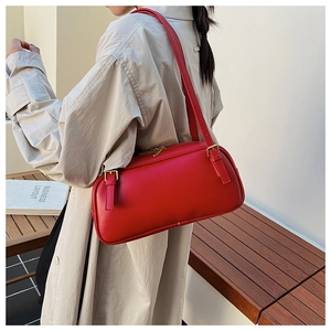 Detail of red leather baguette bag with gold metal zippers worn with an oversized shirt