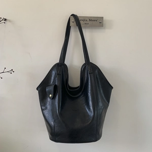 Détail d'un grand sac hobo noir en cuir avec mini pochette assortie sur un cintre