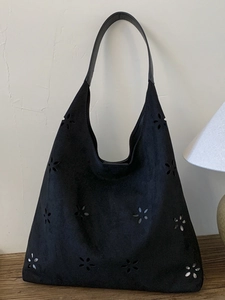 Chic black laser-cut floral tote bag with a minimalist crescent shape and faux suede finish
