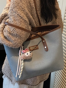 Fashionable contrast-color canvas tote bag with brown leather handles and sloth charm
