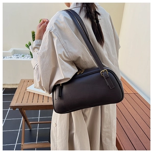 Detail of dark brown vintage faux leather baguette bag with gold metal zippers and buckles