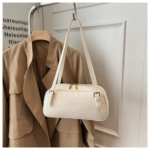 Detail view of cream rectangle underarm bag with gold metal buckle and smooth faux leather