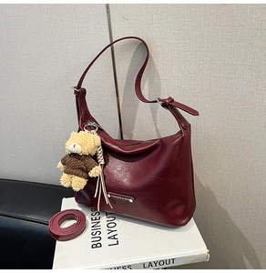 Detail of wine red tote bag with crescent moon shape and cute bear pendant accessory