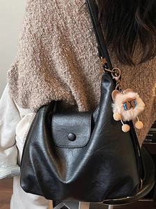 Minimalist black leather tote bag with a cute lion plush pendant for women