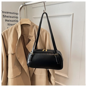 Detail of black matte leather shoulder bag with gold hardware and double zipper closure
