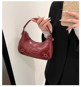 Close-up of wine red patent leather shoulder bag with buckle and clearing logo