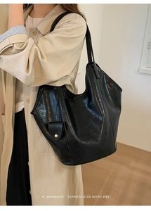 Détail d'un sac cabas en cuir noir avec fermoir magnétique doré au style rétro épuré
