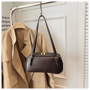 Detailed view of dark brown baguette bag with golden zippers and leather strap buckles