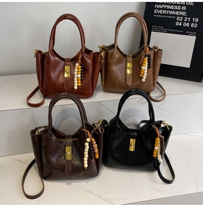 Detalle de bolsos bombonera retro en cuero de cuatro colores con dijes y cierres metálicos