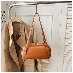 Close-up of caramel leather shoulder bag with golden buckles and dual zippers
