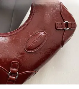 Detailed macro shot of vintage burgundy leather handbag featuring silver metal hardware