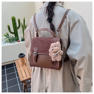 Detail of vintage brown patchwork backpack with quilted flap and cute teddy bear charm