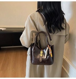 Vista trasera de una modelo con bolso retro de cuero marrón y colgante de cuentas