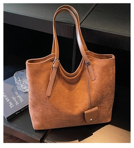 Détail d'un grand sac cabas en daim marron avec bandoulière réglable et pendentif