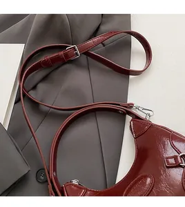 Detail of adjustable shoulder strap with silver buckle on wine red faux leather handbag