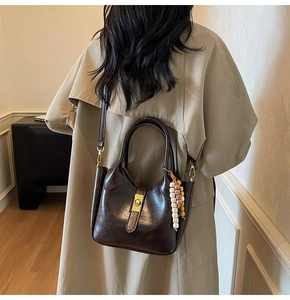 Detalle de bolso vintage marrón oscuro con cierre dorado y asa decorada con cuentas