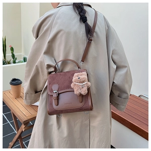 Brown quilted crossbody bag with plush bear charm worn by a model in a trench coat
