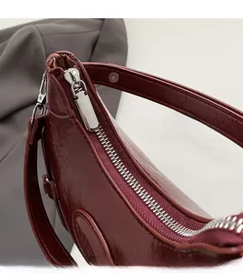 Detailed macro view of the smooth silver zipper and glossy dark red leather texture